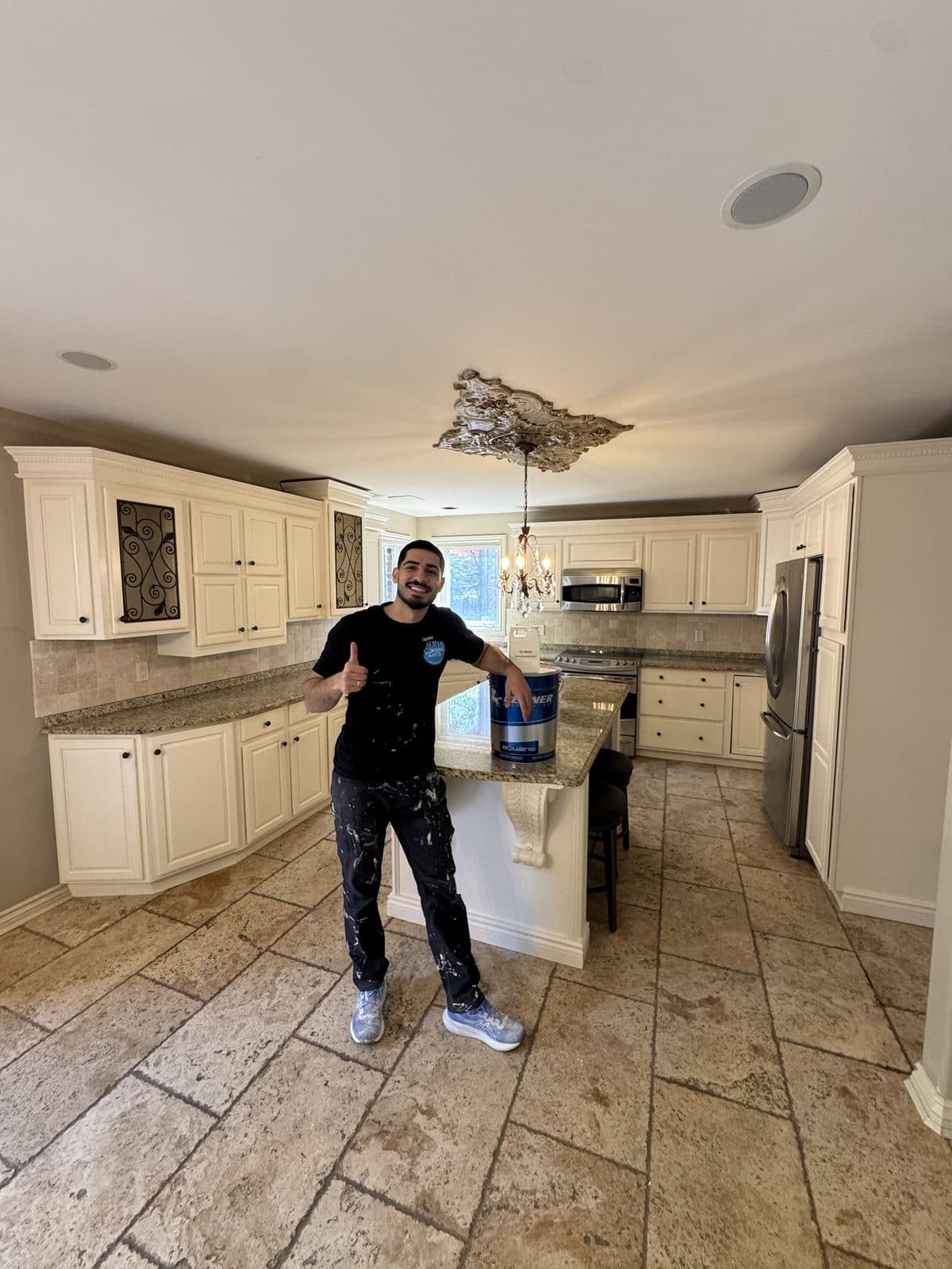Cream kitchen cabinet painting Cream kitchen cabinet painting project with travertine tile and owner holding paint