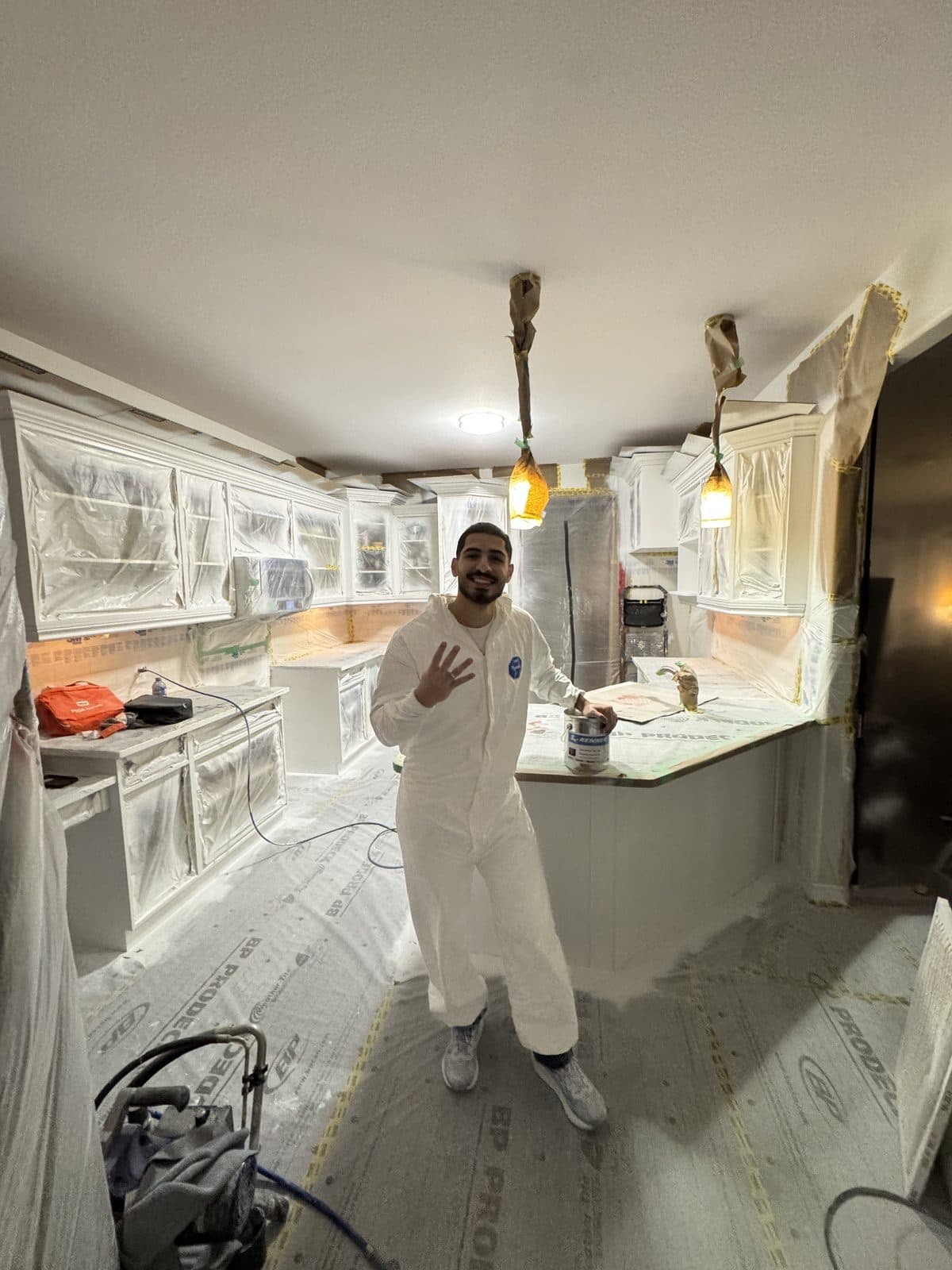 Masked kitchen spray suit primer Masked kitchen with owner in spray suit during primer application