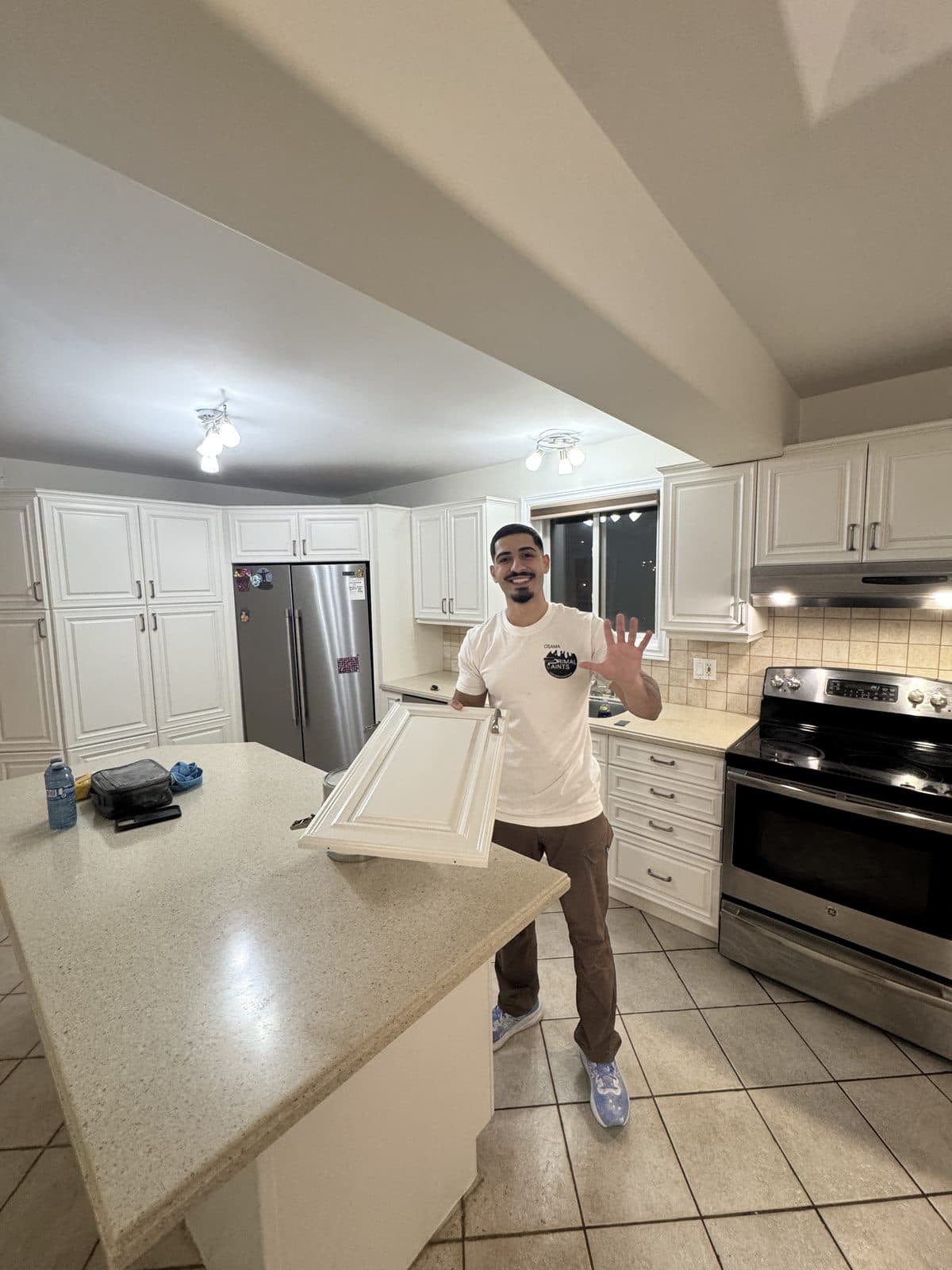 White cabinet door refinish sample Owner holding a refinished white cabinet door inside a bright kitchen