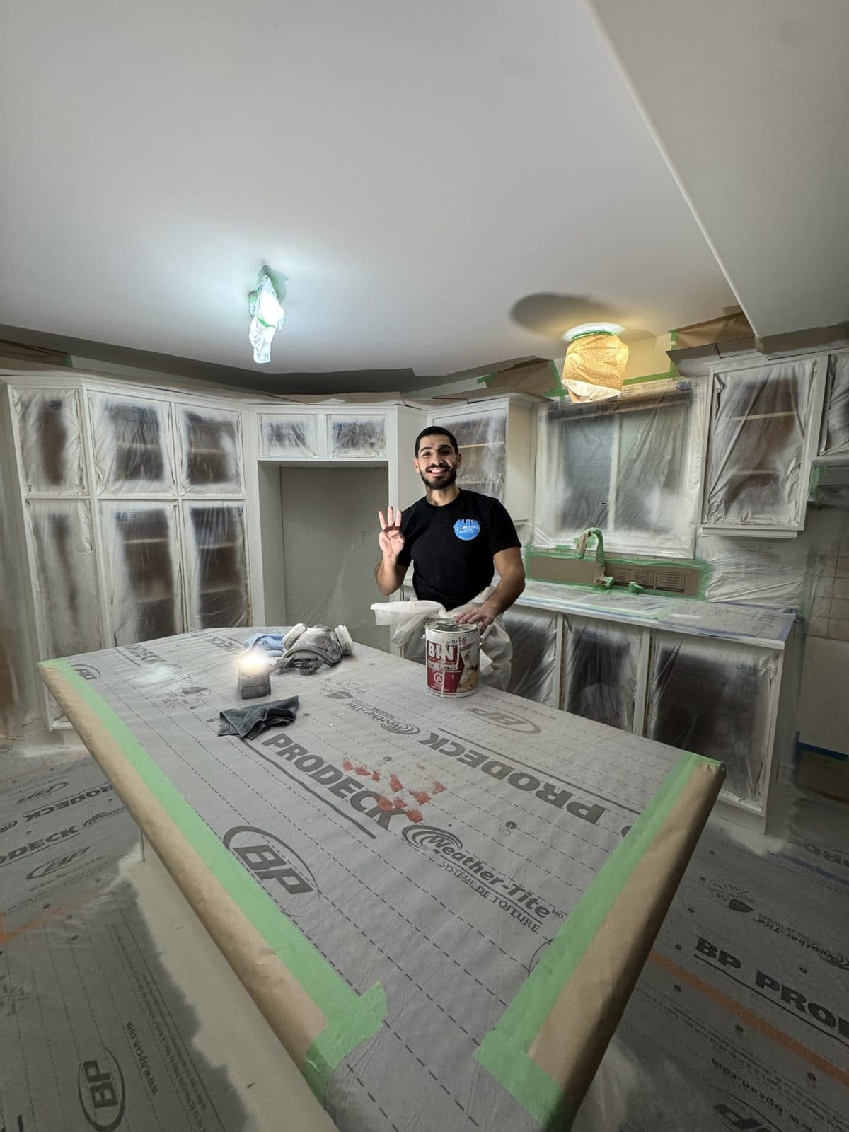 White cabinet spray mask prep Owner in a masked kitchen during white cabinet spray preparation